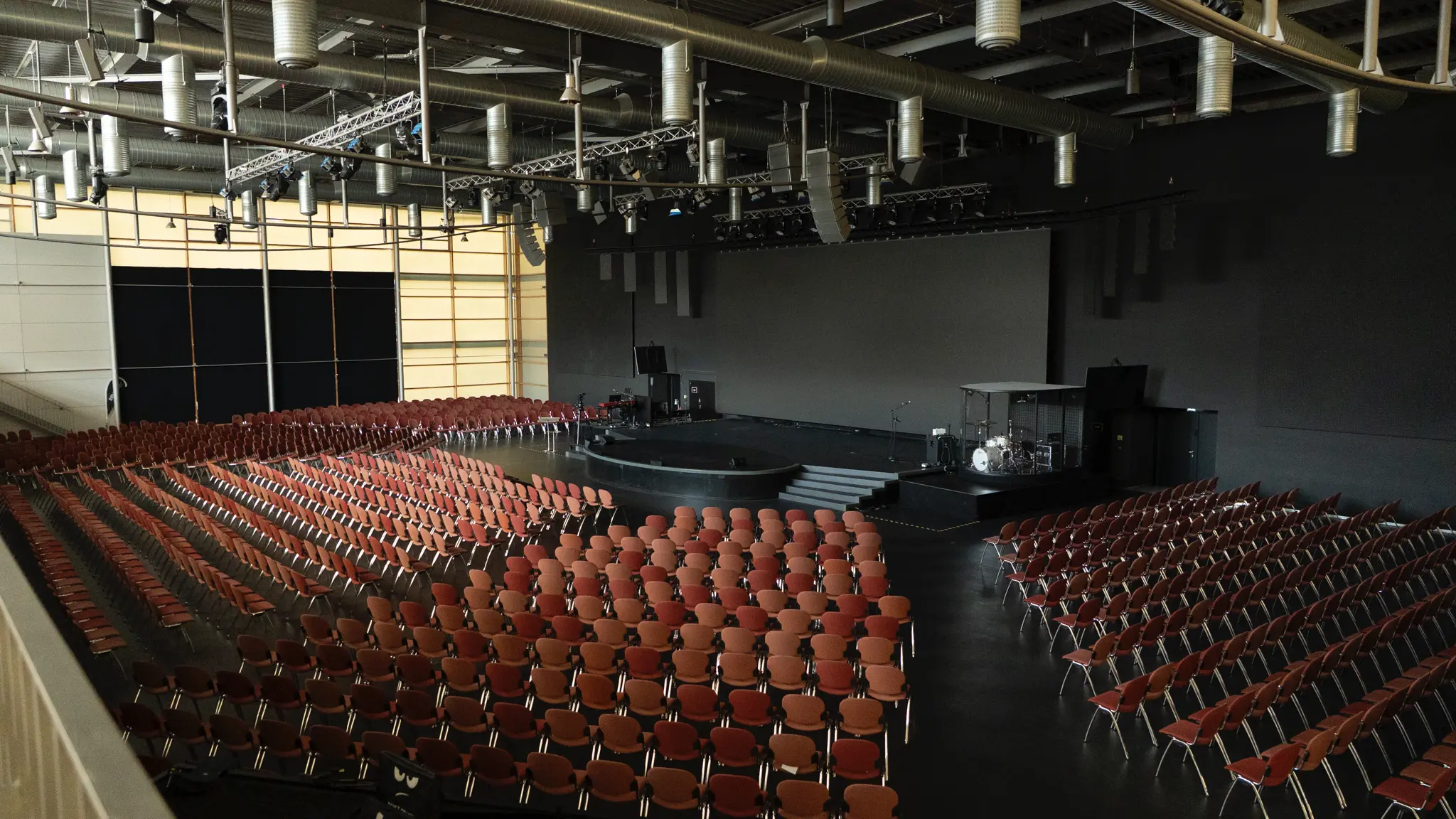 Großer Saal mit Bühne und dunklem Boden